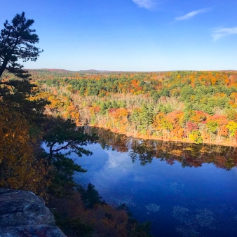 A breathtaking view of a pond seen from the top of a towering cliff.