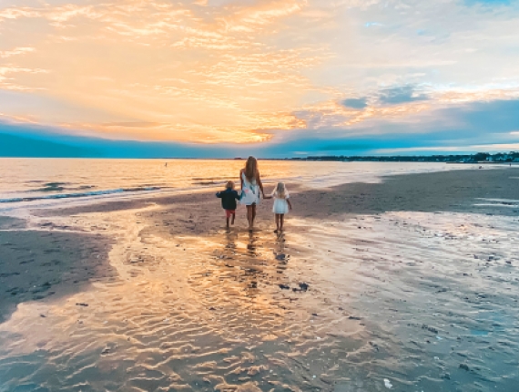 Mom walking along Hammonassett Beach with kids at low tide